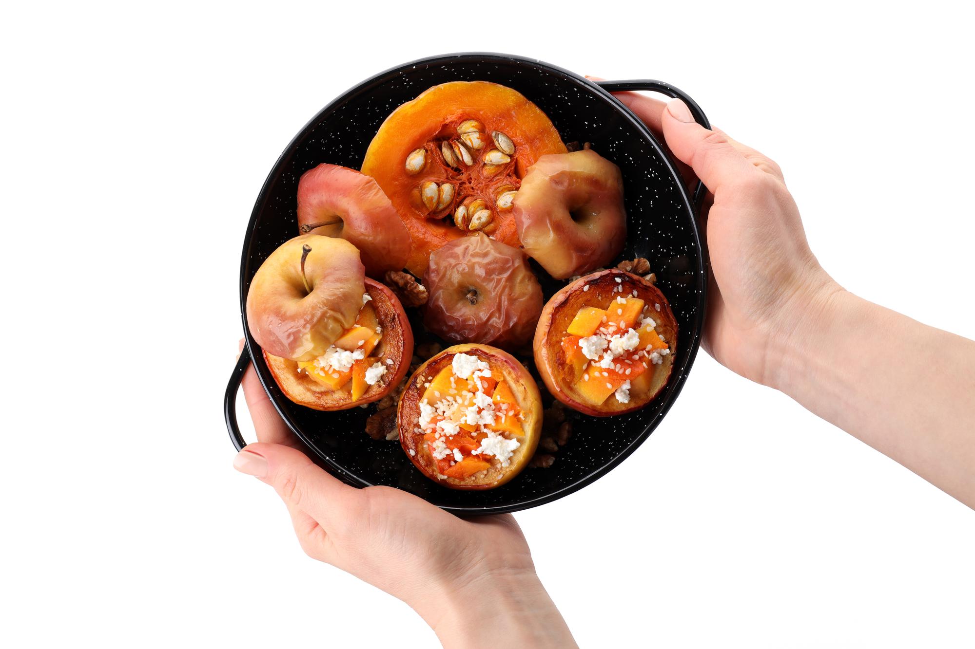 Hand arranging roasted vegetables in bowl